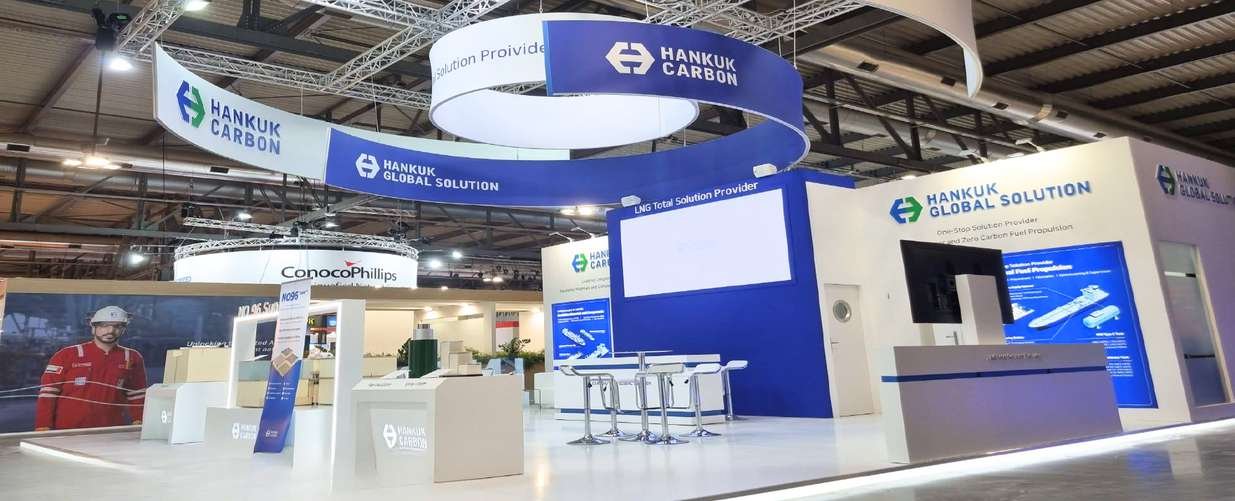 Blue-and-white Hankuk Carbon stand with suspended circular branding and product screens at Gastech in Milan